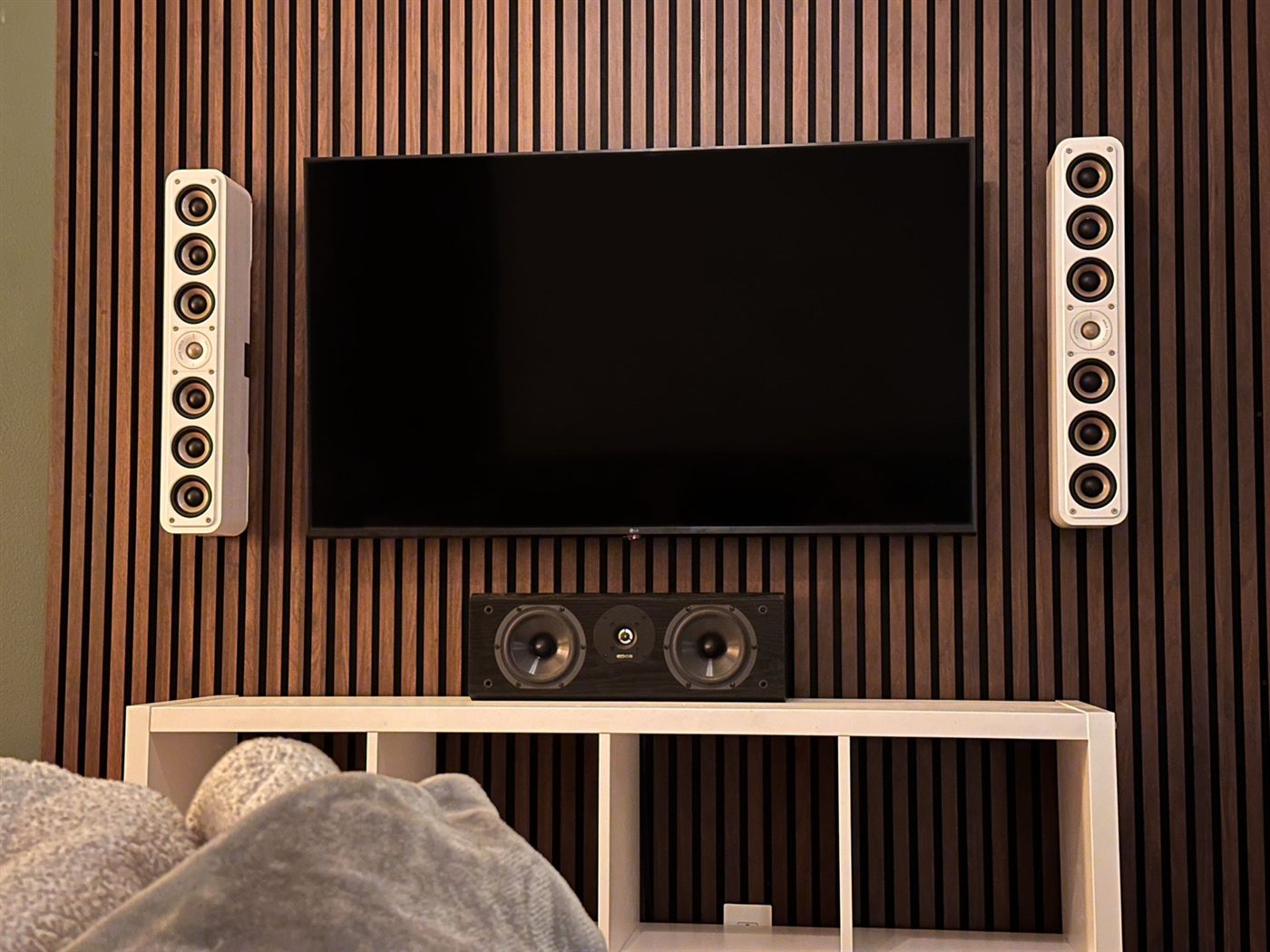 Walnut slat wall with a centred TV, in-wall speakers either side and a centre channel below