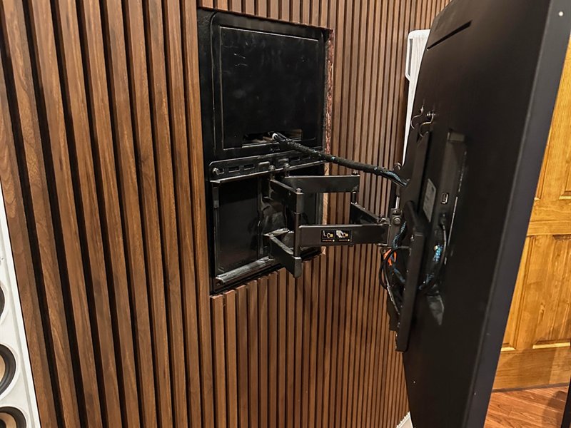 The articulating mount swung away from the wall, showing the recessed box and the cable path behind the TV