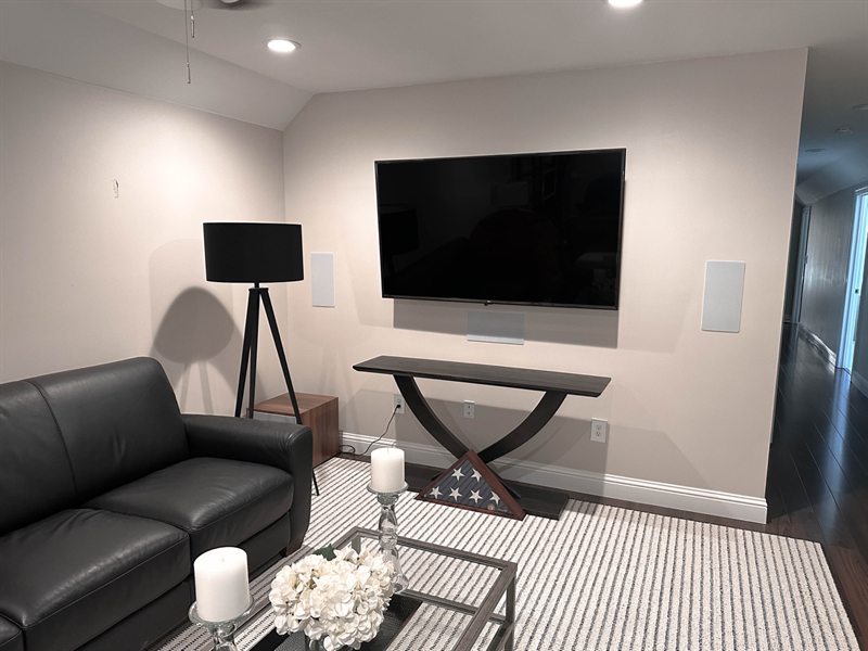 Family room TV mounted flush to the wall with in-wall speakers and a soundbar