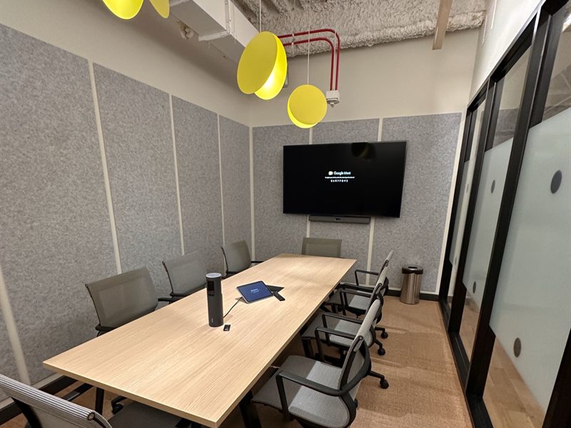Conference room with a glass wall and a wall-mounted display above the table
