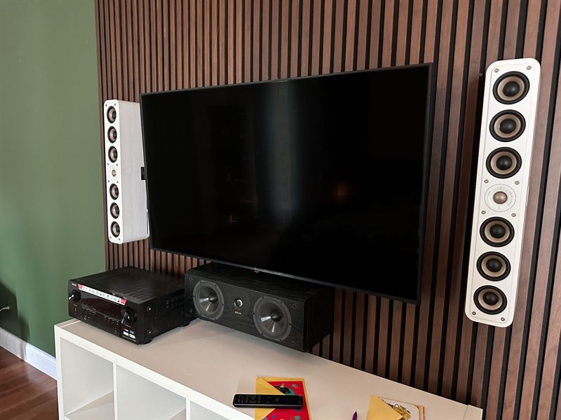Media wall with a mounted TV, tower speakers, center channel, and an AV receiver