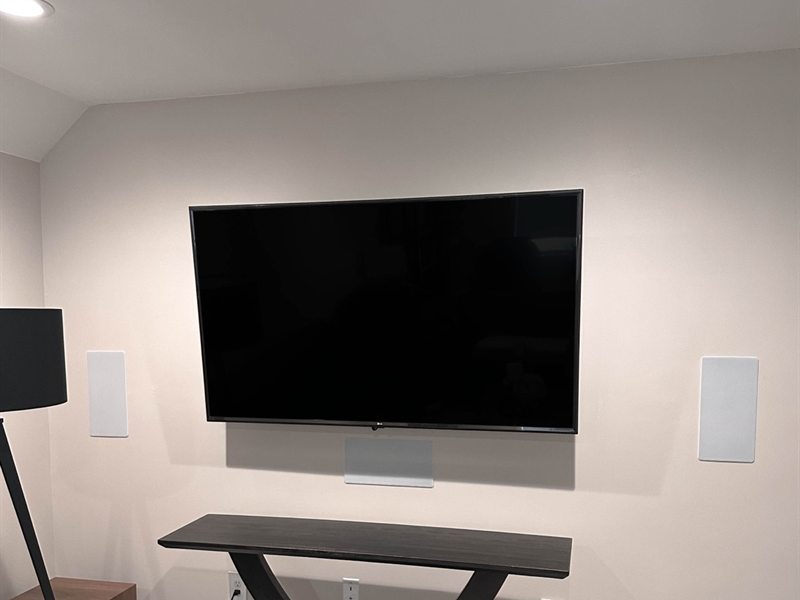 Mounted TV above a console table with in-wall speakers and no visible wiring
