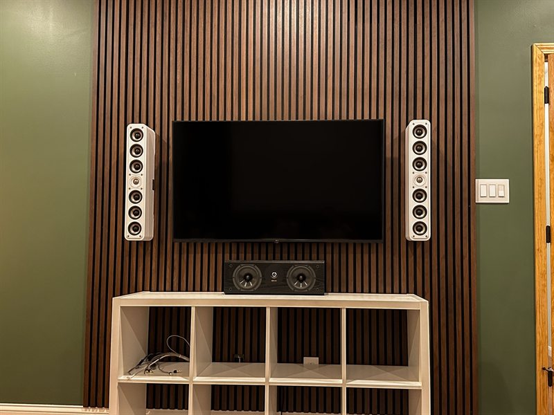 Full walnut slat wall with a mounted TV, tower speakers either side, and a center channel on the console